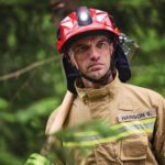 Mann trägt Feuerwehrhelm HEROS H10 mit Helmlampe HL3 Ex